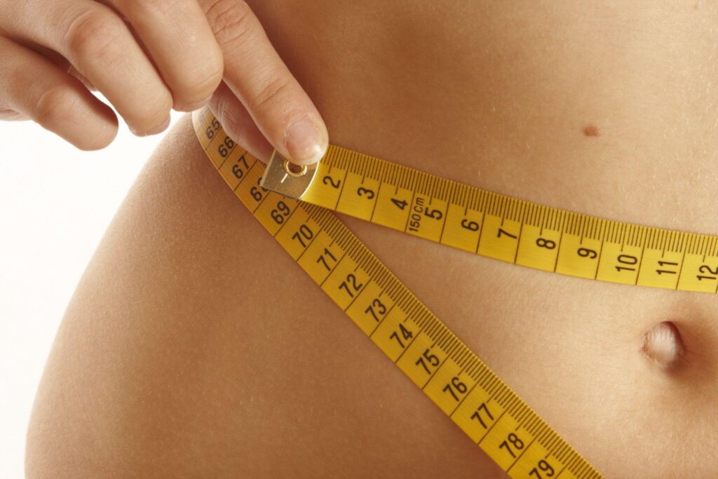 Thin female measuring her waist.
